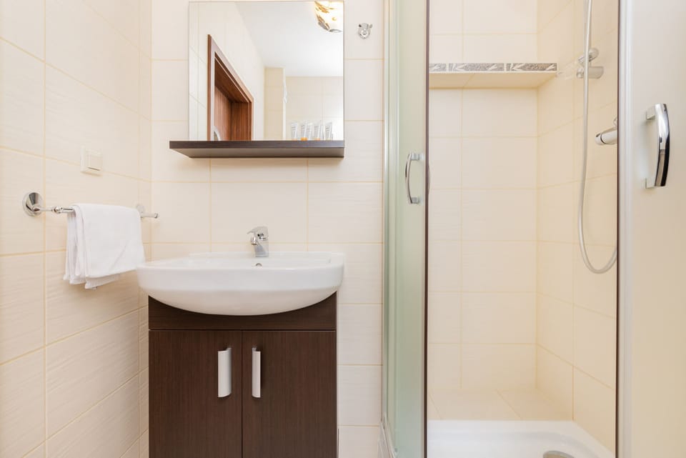 Bathroom corner featuring a white sink, mirror, and compact design for convenience.
