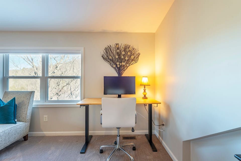 Office area in the primary bedroom equipped with a chair and standing desk.