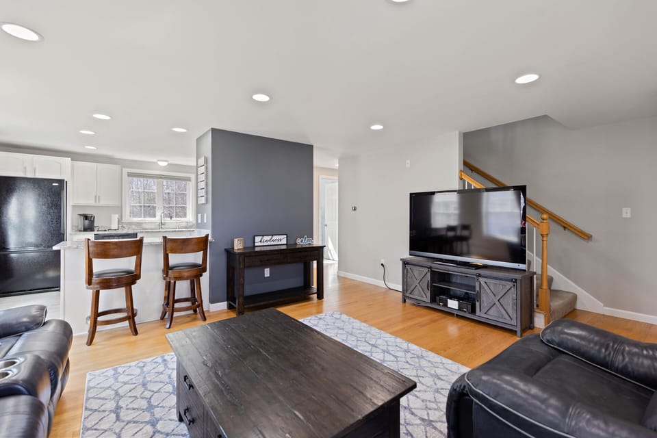 Living room with oversized leather reclining couch, recliner and 60" smart tv