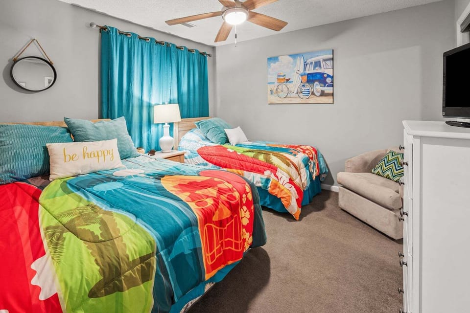 Two beds and a sofa in a colorful bedroom at Sandwedge 206, an Ocean Drive vacation rental