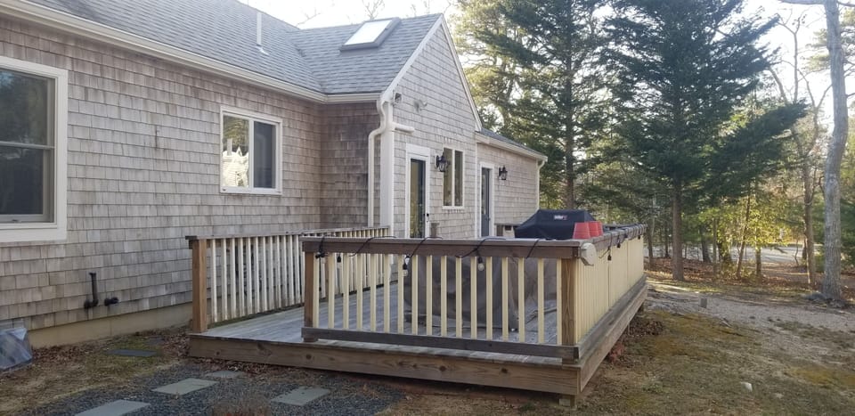 Outside deck with large grill and table that seats 8 people and umbrella.