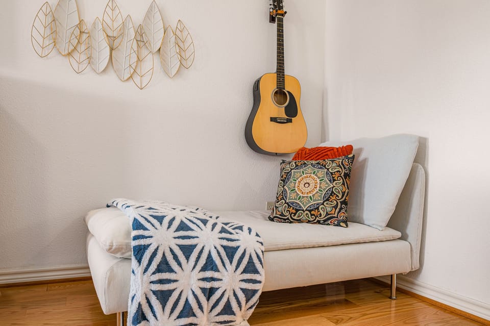 Cool sitting are with guitar in primary bedroom