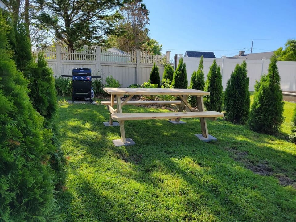 Picnic table, grill, and fire pit in garden area.
