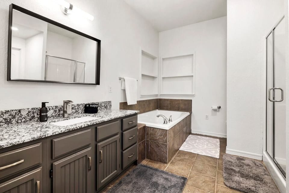 The en suite bathroom features a jacuzzi tub, glass shower, sink, and tons of counter space.