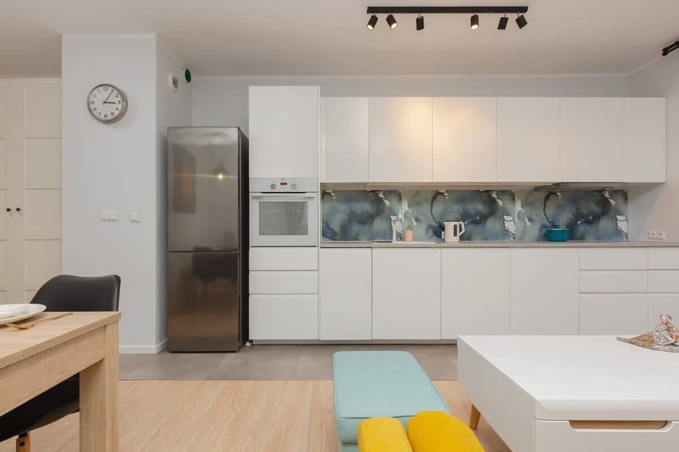 A compact kitchenette equipped with essential appliances, white countertops, and plenty of storage space. Bright lighting enhances its clean look.