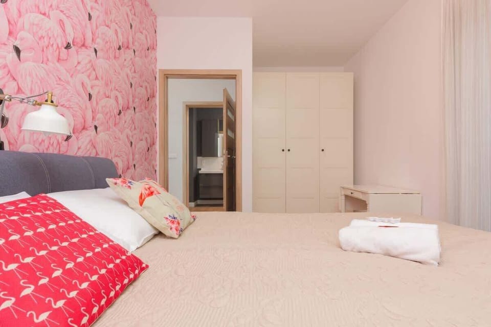 A different angle of the bedroom showing the bed, a mirrored wardrobe, and a bedside table. The room feels cozy and functional.