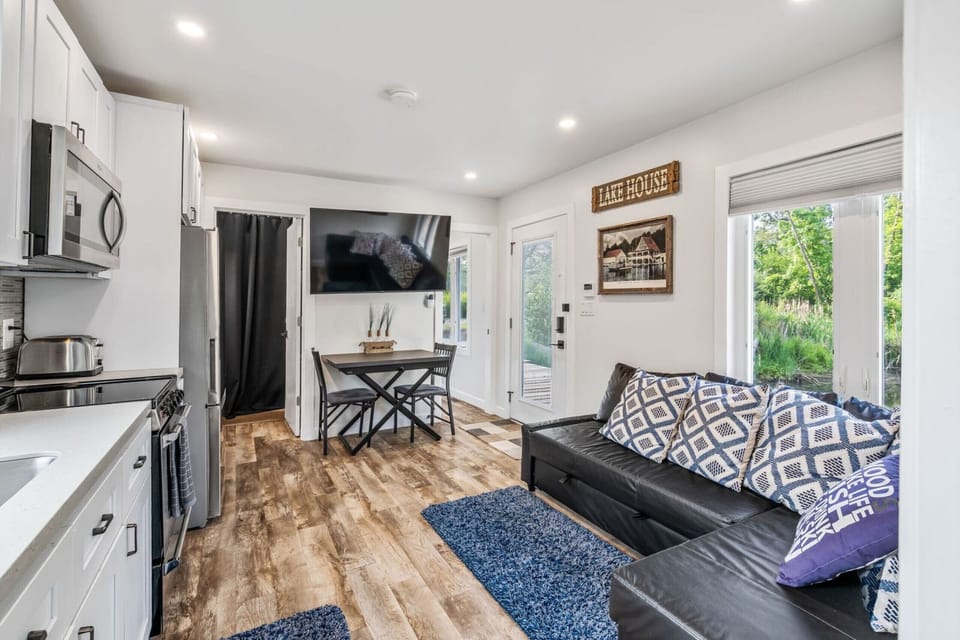 Open living space featuring modern kitchen, cozy pull-out sectional sofa, and dinging area with views of the peaceful marina surroundings.