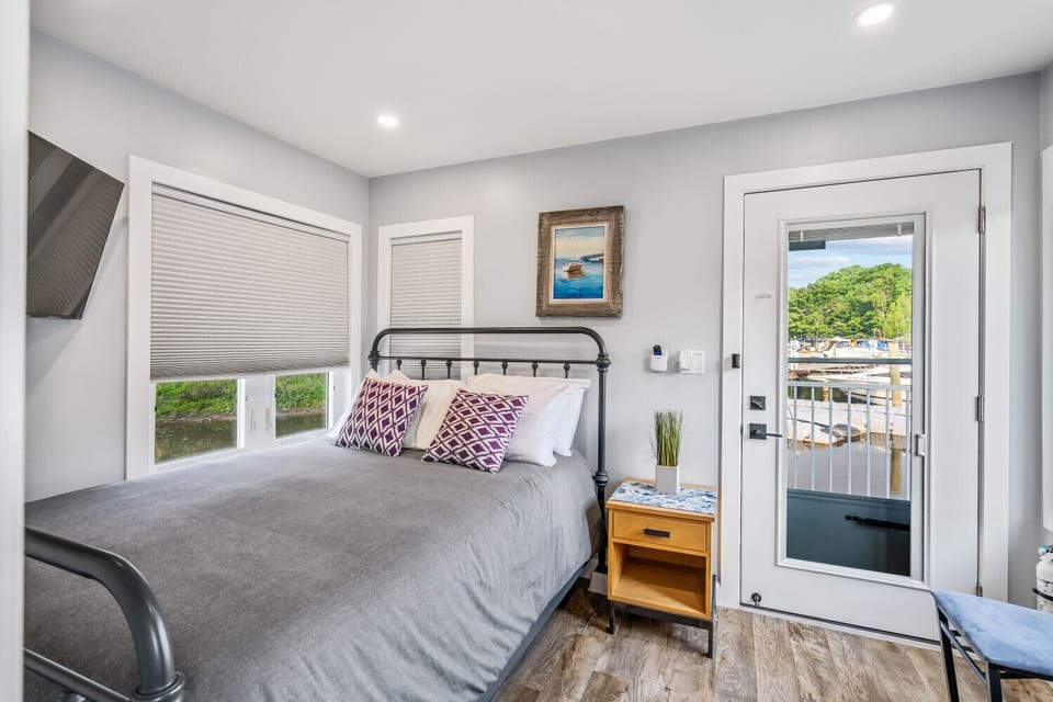 Waterfront bedroom featuring cozy bed and a private door leading to the outdoor deck.