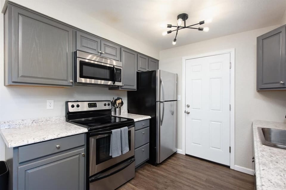 The kitchen features beautiful countertops and modern appliances, including refrigerator, stove, oven, microwave and coffee maker.