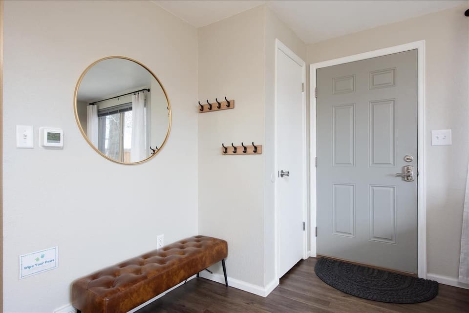 The stylish and inviting entryway with mid-mod bench, brass mirror and industrial hooks greet you upon arrival.
