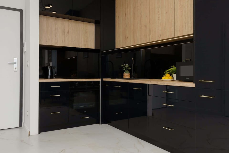 A stylish kitchen in black and wood tones, equipped with modern appliances and a minimalistic design.

