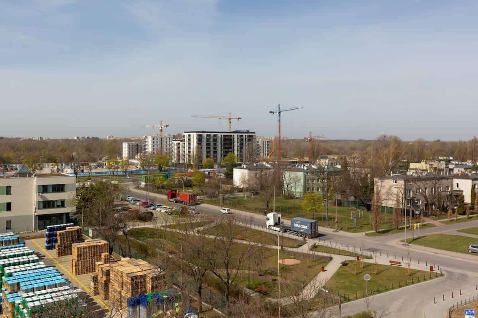 Another perspective of the balcony showing neighboring buildings and a green space below.