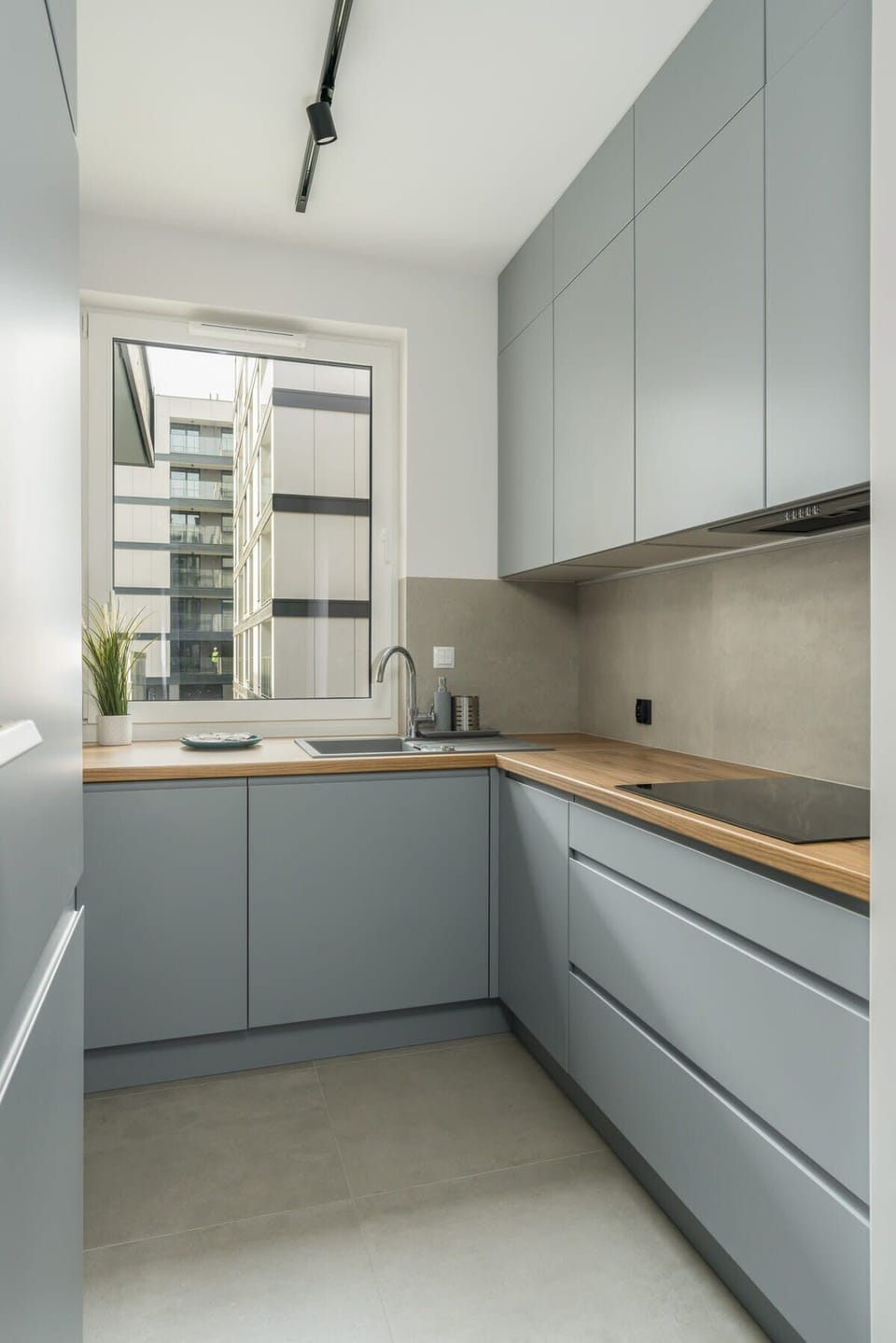 A modern kitchen with sleek gray cabinets, minimalistic design, and stainless steel appliances.