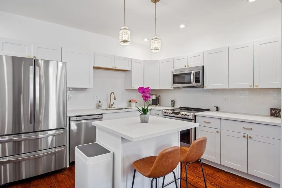 Bright, modern kitchen with sleek white cabinetry, stainless steel appliances, and a stylish island for dining or prep. Clean finishes and thoughtful design make it both functional and inviting.