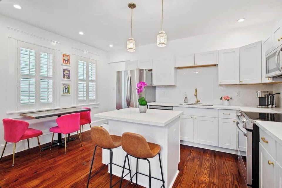 Sun-filled kitchen with crisp white finishes, a central island, and stainless steel appliances. A cozy dining nook by the windows adds charm—perfect for morning coffee or casual meals.
