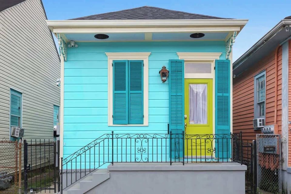 Charming New Orleans cottage with vibrant colors, classic shutters, and a welcoming front porch. Bright curb appeal sets the tone for a stylish and memorable stay.