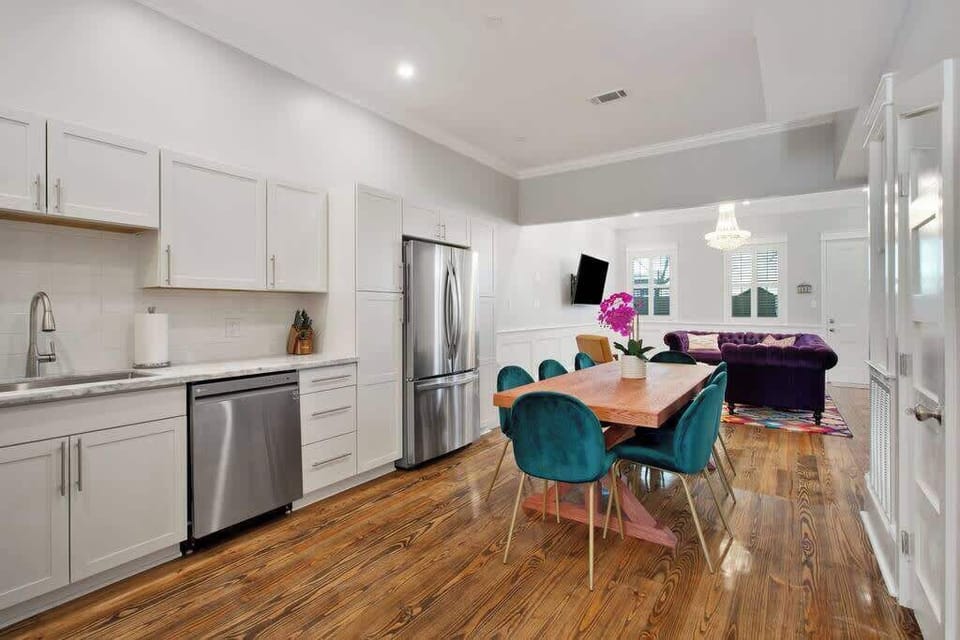 Modern open-concept kitchen and dining area with stainless steel appliances, quartz counters, and stylish seating. Flows seamlessly into a vibrant living space—perfect for group meals, entertaining, or relaxing after a day exploring the city.