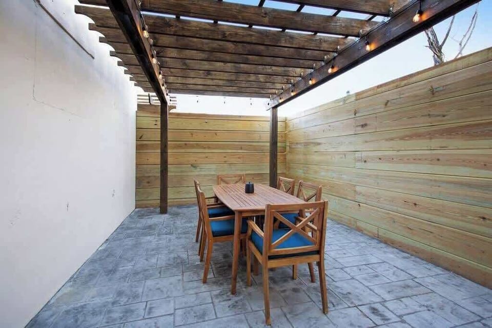 Private outdoor patio with a pergola, string lights, and dining seating. A cozy, shaded space perfect for morning coffee, evening drinks, or enjoying meals in a relaxed setting.