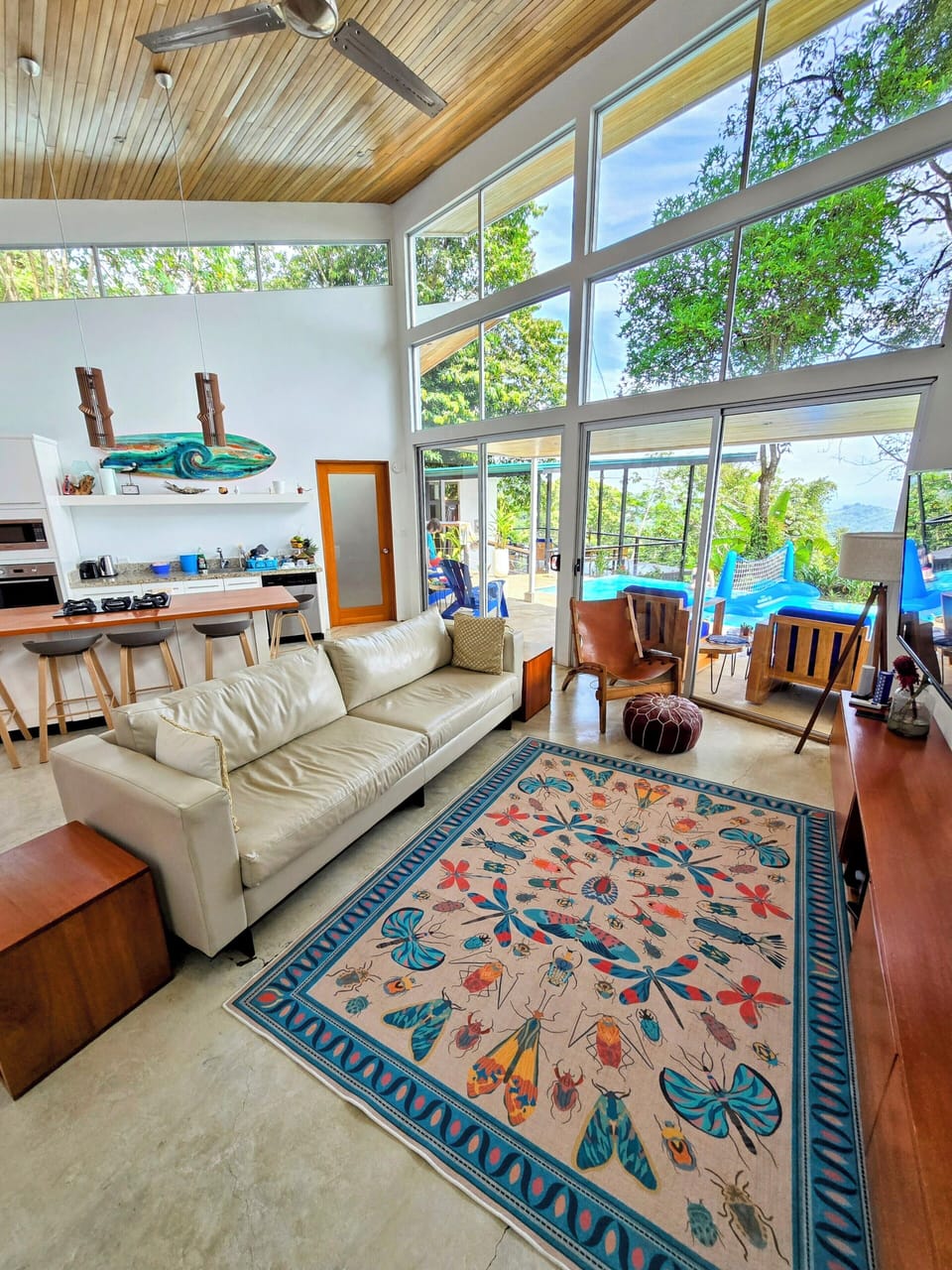 Modern bright open plan living room/kitchen, floor to ceiling windows. AC & fan