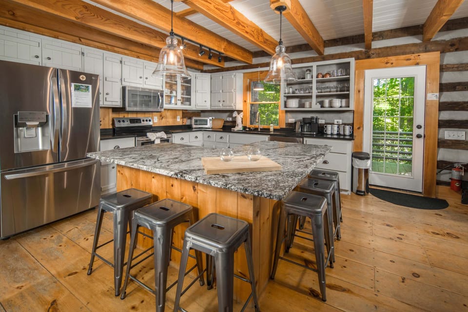 The fully equipped kitchen features granite countertops, stainless steel appliances, and island seating for six