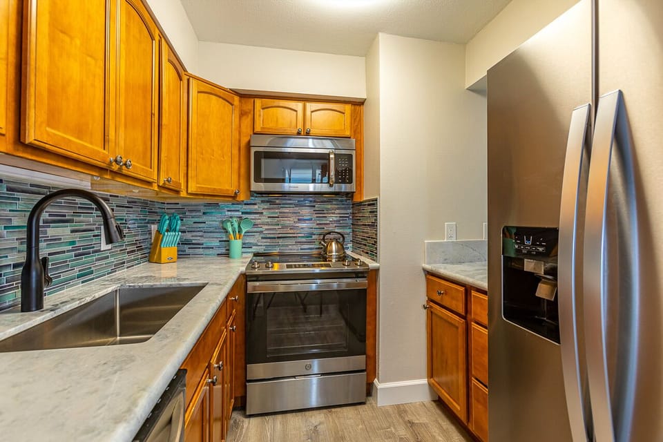 Your fully equipped kitchen features stainless steel appliances, granite countertops, and a colorful mosaic backsplash—ready for you to prepare your favorite meals during your stay.