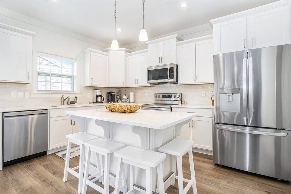 Fully equipped kitchen with stainless steel appliances, a spacious island, and seating for four.