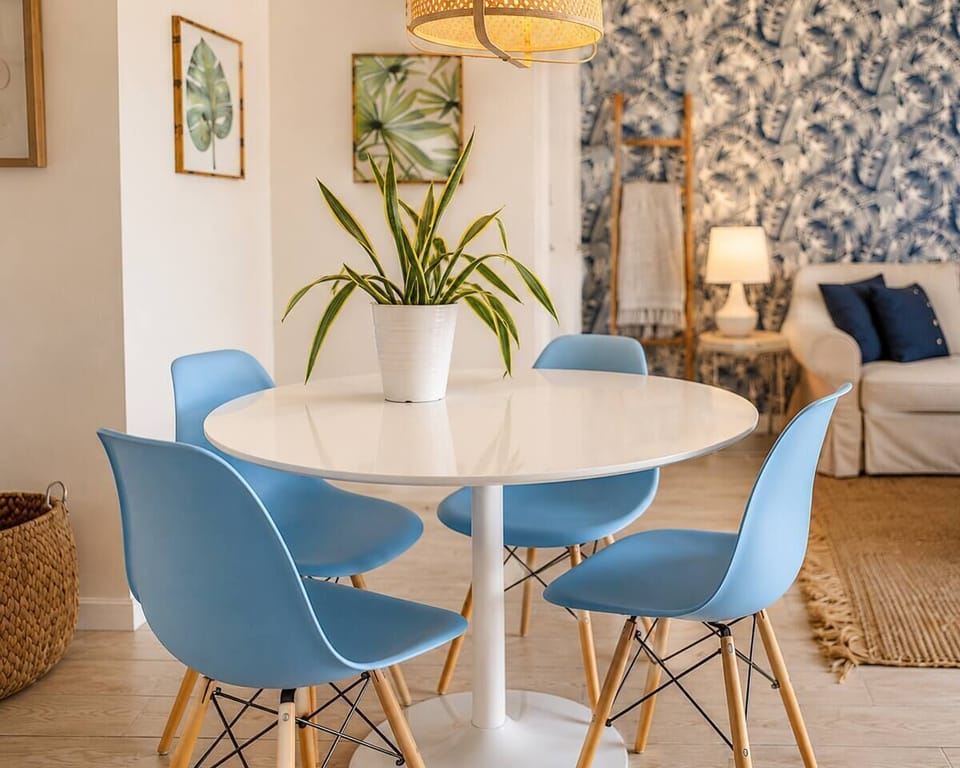 Morning coffee at the white circular dining table before heading to the beach; the botanical wallpaper and nearby city skyline views make this a bright spot for breakfast.