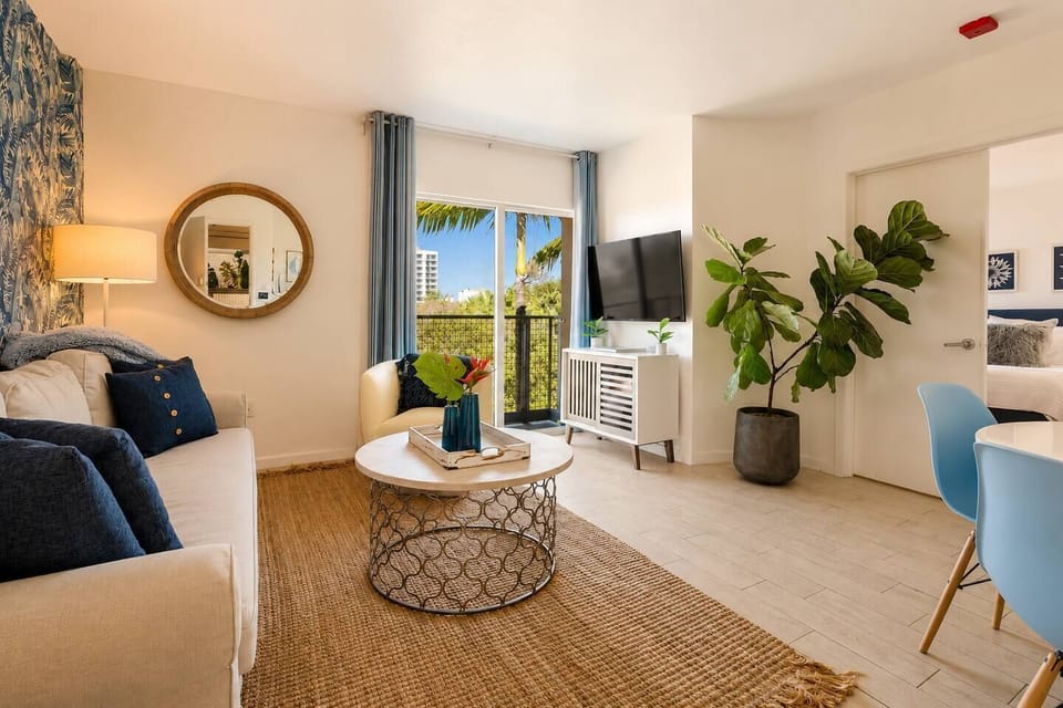 The white media console sits beneath the TV for movie nights, while the glass doors open to your private balcony for views of the city skyline.