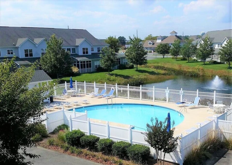 The pool features loungers, tables, and umbrellas, a bathroom and shower. 