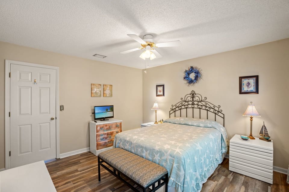Cozy linens, seaside decor, soft lighting, and ceiling fan for restful nights.