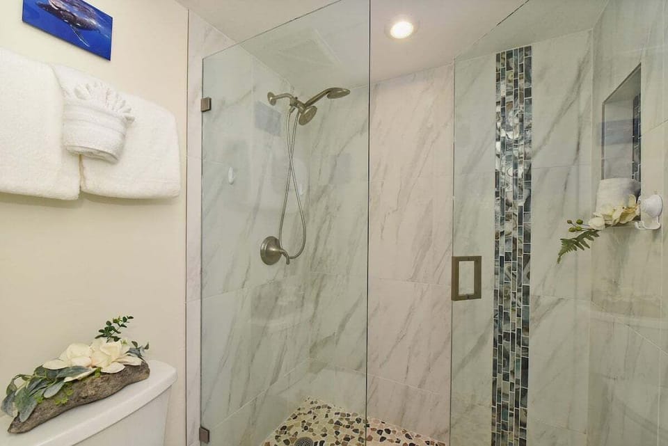 Step into a spa-like escape with this stunning walk-in shower featuring elegant marble tile and a pebble floor.