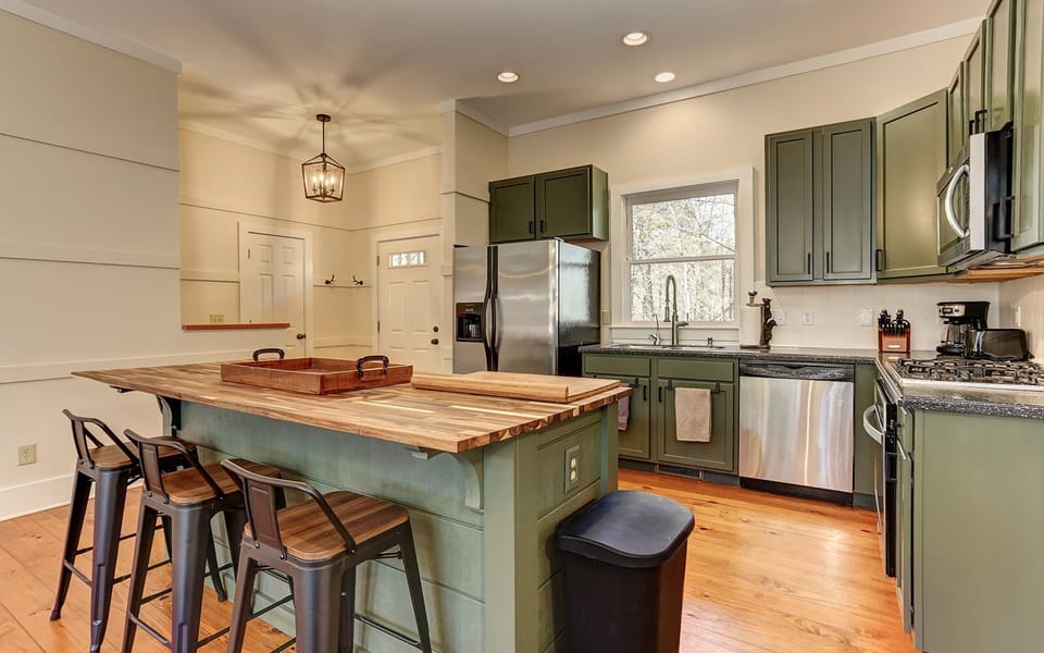 Elegant green cabin kitchen with modern lighting.