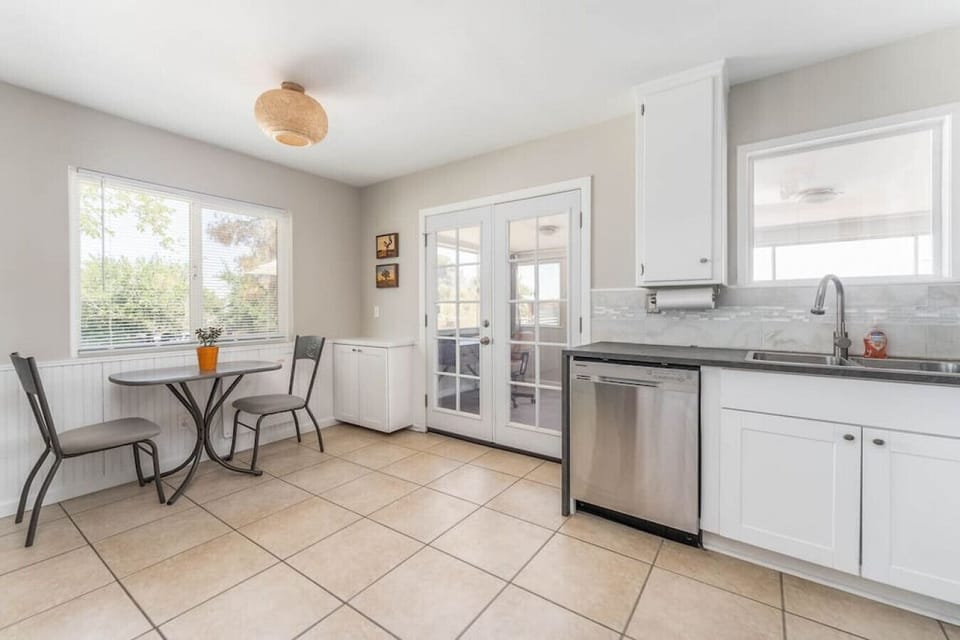 Full kitchen and seating area with stainless dishwasher, entrance to sunroom in back
