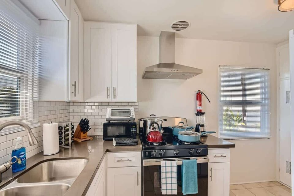 Enjoy the full kitchen with a refrigerator, oven, stove, microwave, coffee, creamers, mixers, spices, pots, pans, cooking supplies, cutlery, cups, plates, bowls, utensils, small appliances, view of the backyard, and many more essentials.