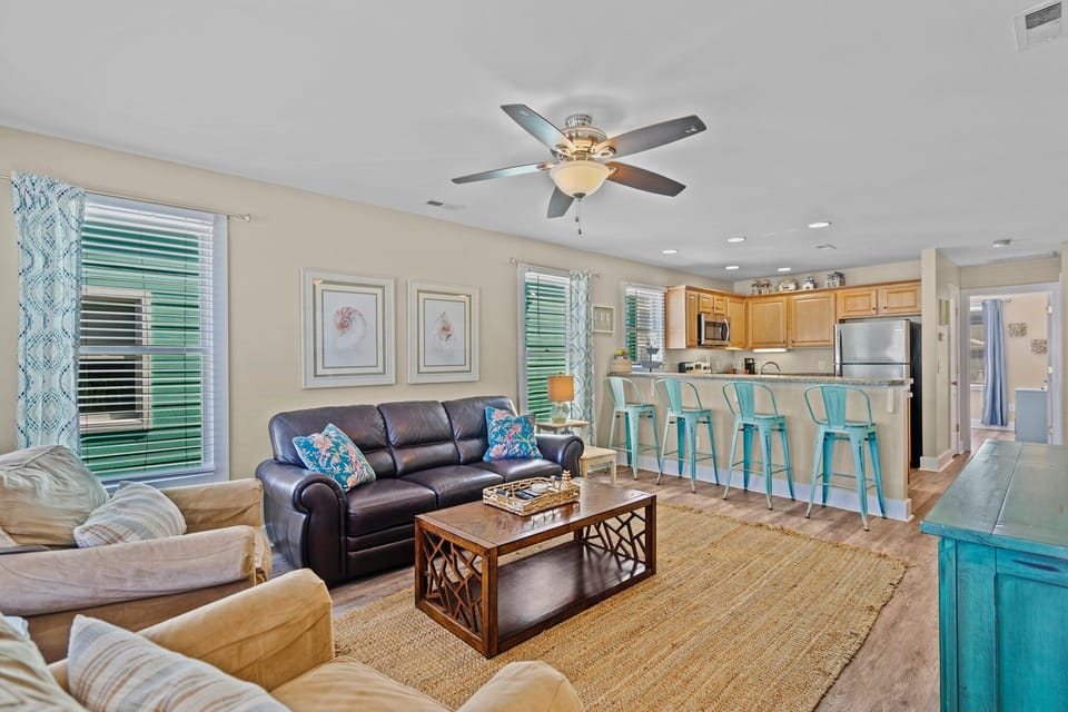 Relax in your bright, open living space where coastal blues meet warm comfort. The kitchen's breakfast bar invites morning coffee moments.