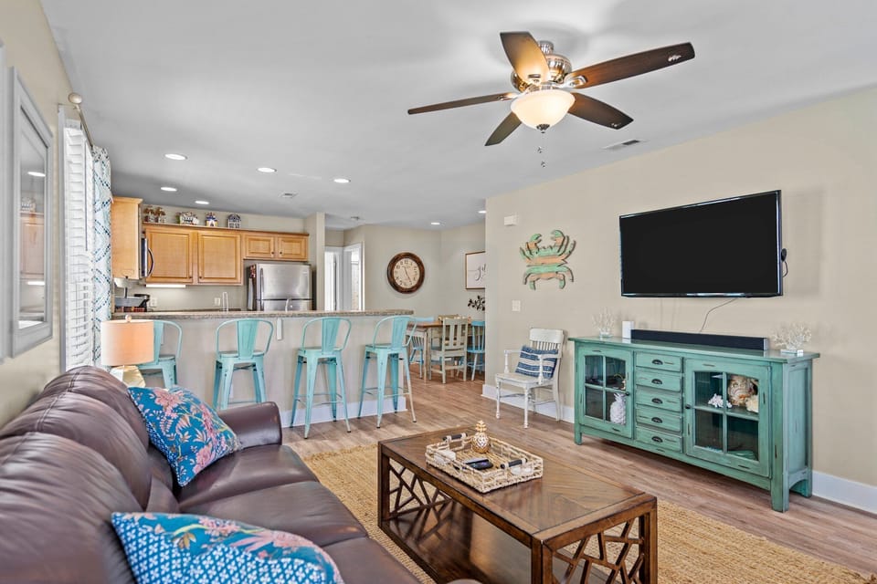 Relax in your coastal-themed living space with comfortable seating, a large TV, and an open kitchen perfect for vacation meals.