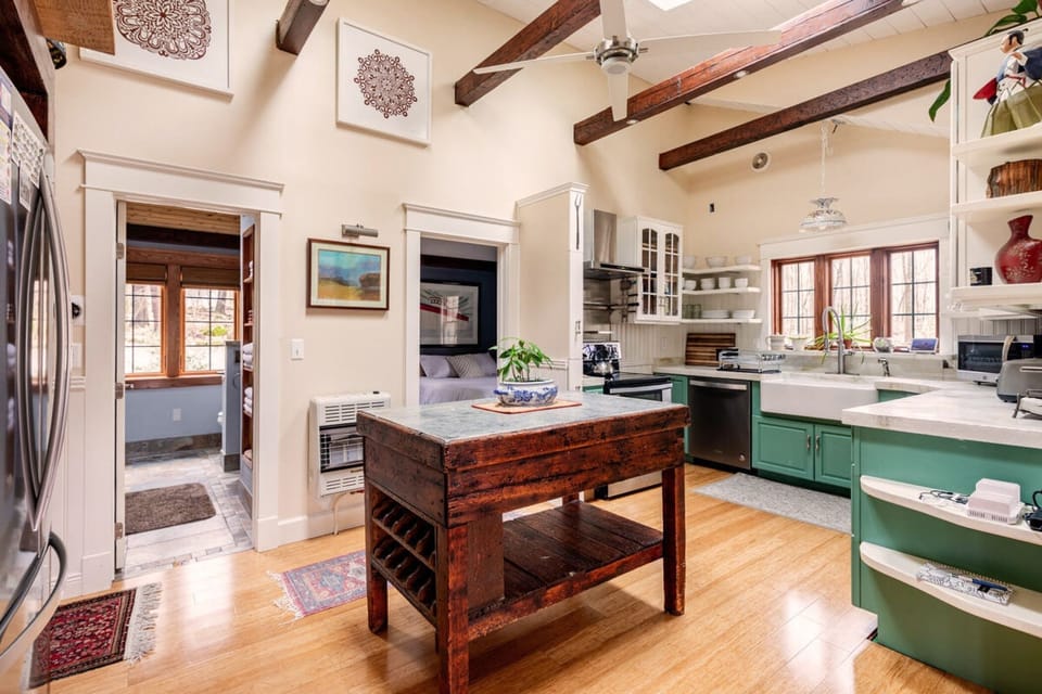 Completely renovated in July 2022, the kitchen features a skylit ceiling with distressed timbers, dramatic lighting, an antique granite island, concrete countertops, all-new appliances, bamboo flooring, maple cabinetry, and Italian farmhouse sink.