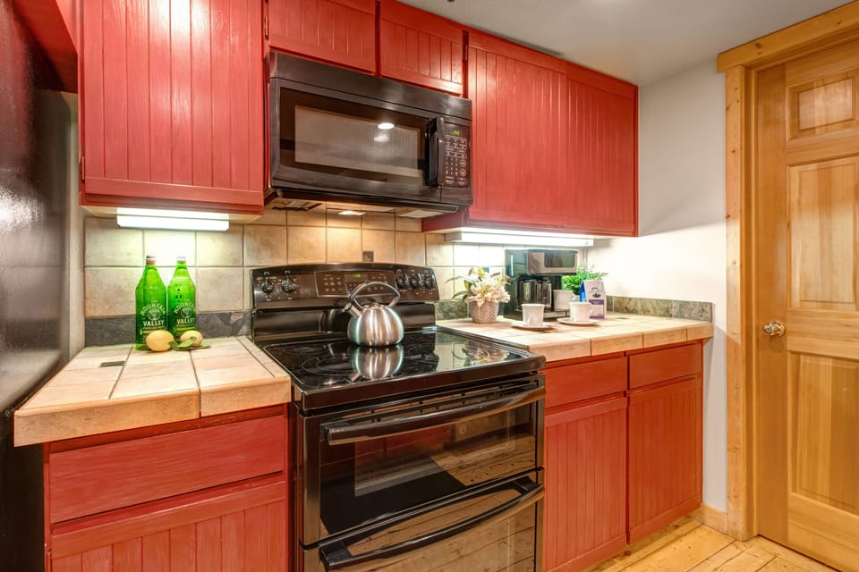 Fully Equipped Kitchen with tiled countertops, double oven, full bath access and bar seating for 3