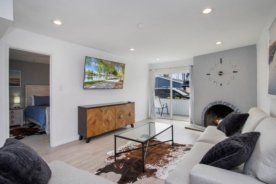 Living room with original Newport Beach art, fire place, and 65" 4k flatscreen