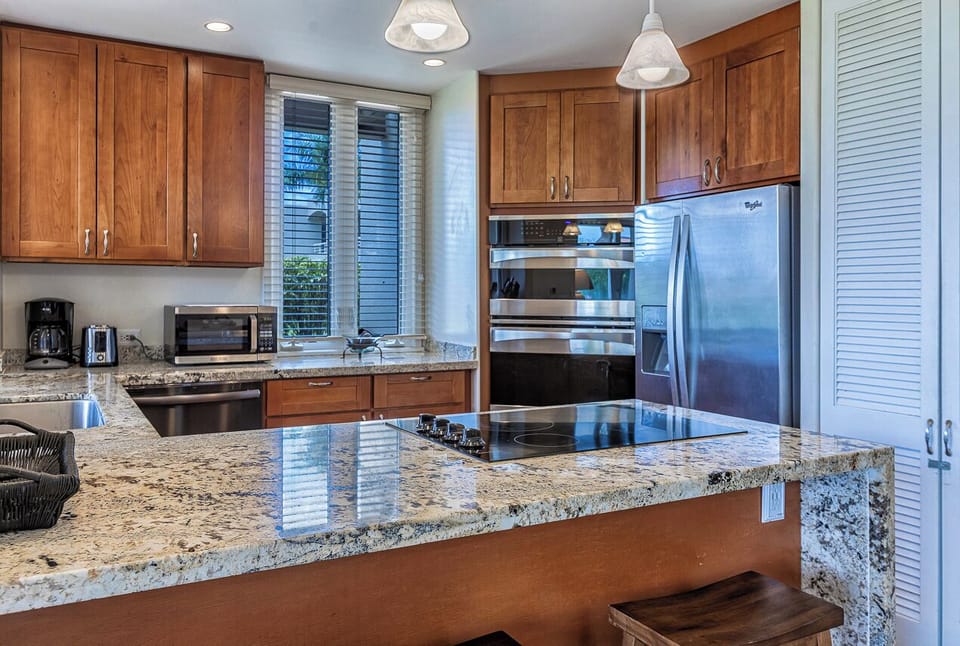 Your gourmet kitchen features gleaming granite counters, stainless steel appliances, and a central island cooktop—perfect for preparing meals together or enjoying morning coffee with garden views.