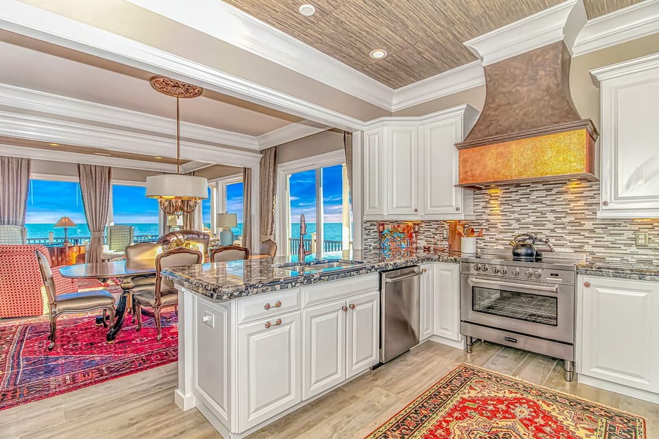 Cook with endless ocean views through floor-to-ceiling windows in this elegant kitchen featuring granite countertops and premium appliances.
