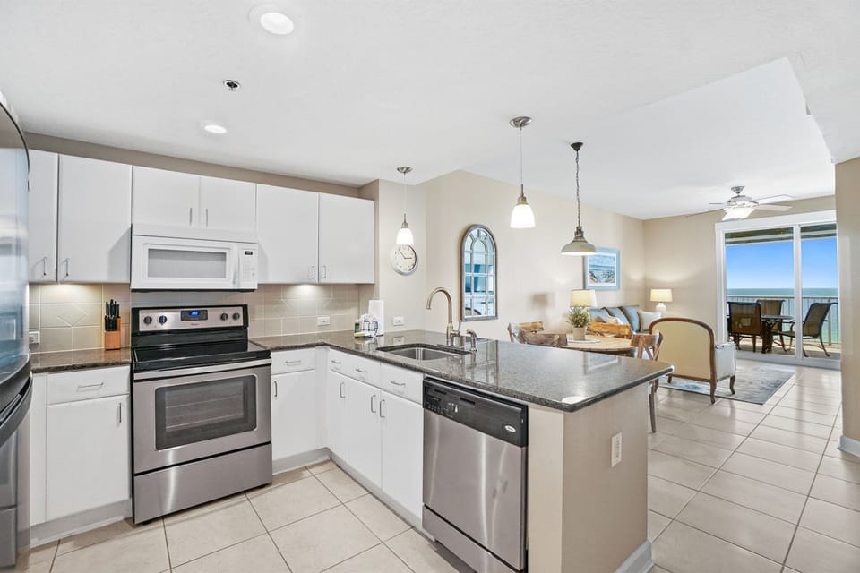 Your bright modern kitchen opens to the living area, perfect for preparing meals while enjoying ocean views through floor-to-ceiling windows.