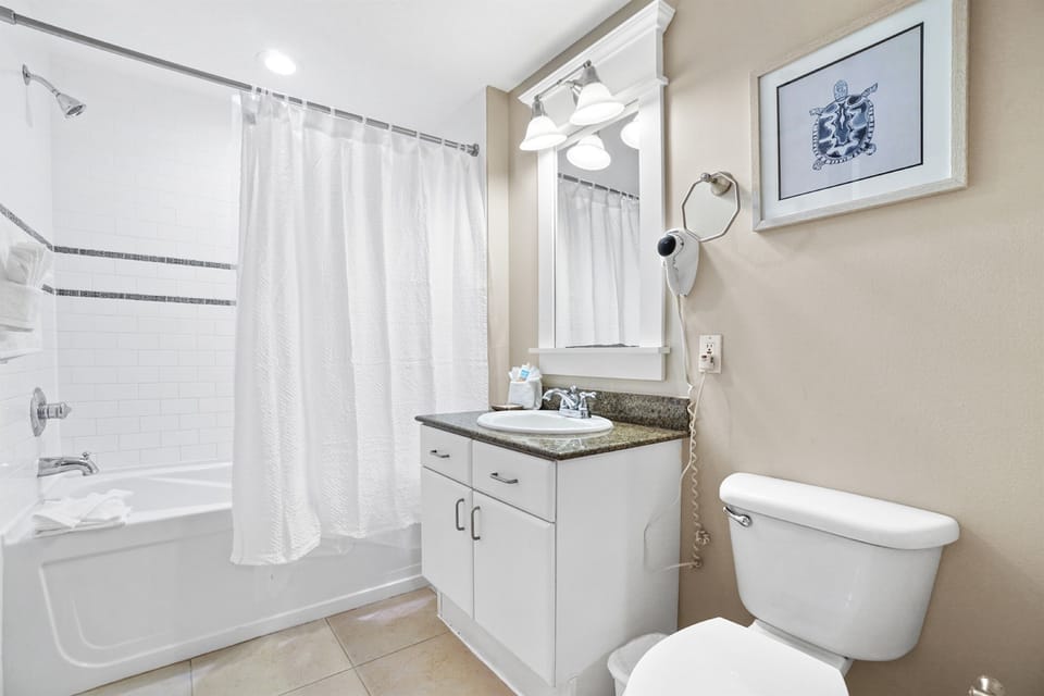 Step into your pristine bathroom featuring a granite vanity, spacious tub-shower combo, and modern amenities for your comfort.