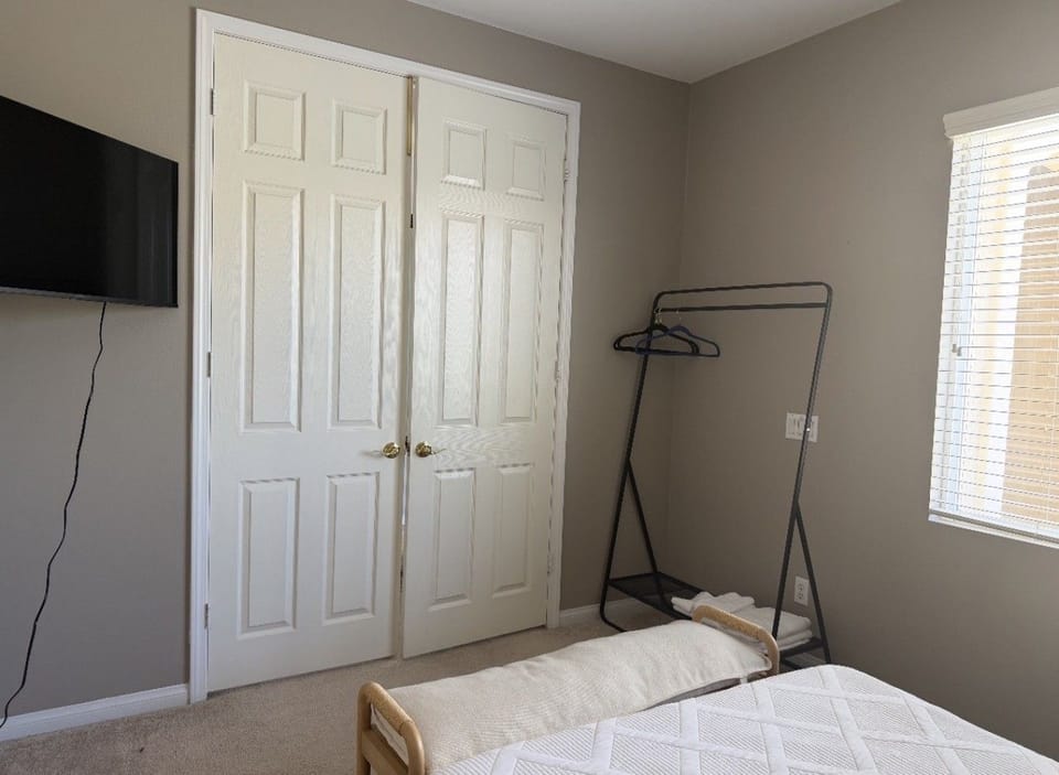 Second bedroom with a clothing rack and TV
