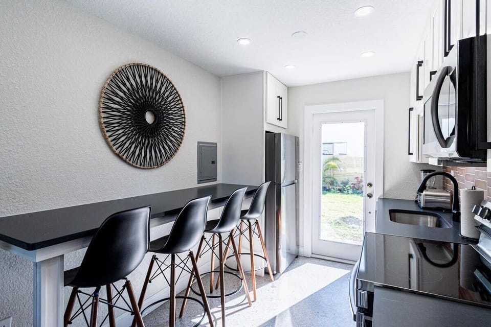 Modern kitchen with a breakfast bar and stainless steel appliances overlooking the backyard.