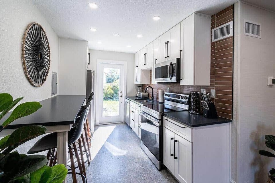 Modern kitchen with stainless steel appliances and a breakfast bar with seating.