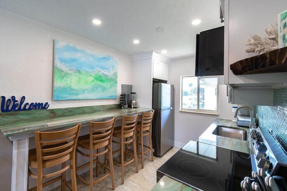 Modern kitchen with a green marble countertop and bar seating for four.