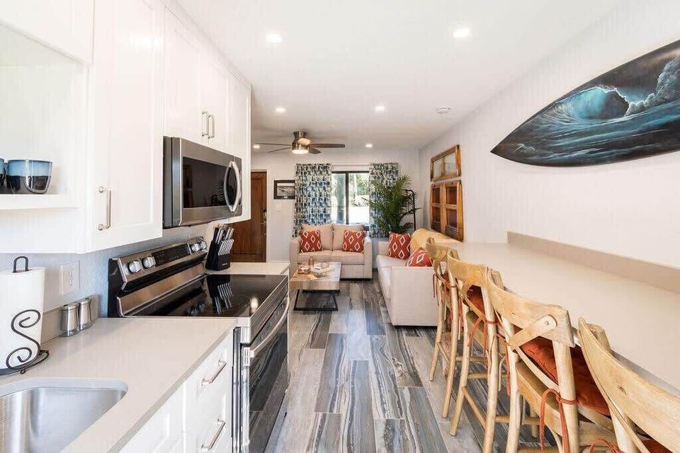 Modern kitchen and living area with a coastal-inspired design and bar seating.
