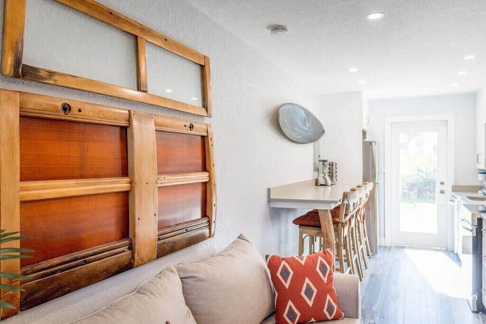 Bright kitchen with a breakfast bar and wooden stools overlooking the living area.