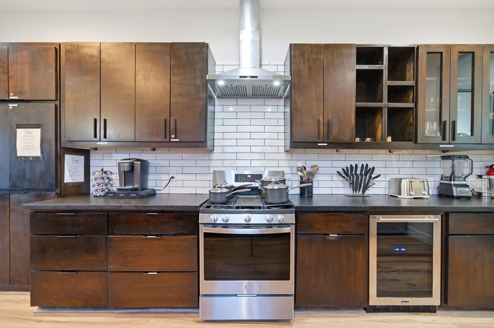 Modern kitchen with gas range, wine fridge, and sleek dark wood cabinets